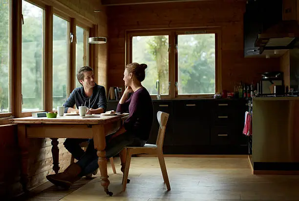 Full length of young couple having breakfast at table in cottage