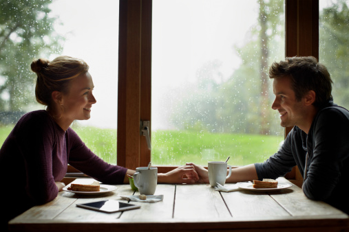 Side view of loving young couple looking at each other while having breakfast in cottage