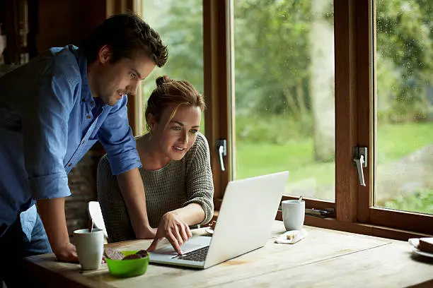 Young couple using laptop at table in cottage
