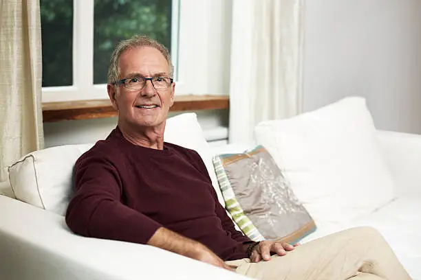 Portrait of confident senior man sitting on sofa at home