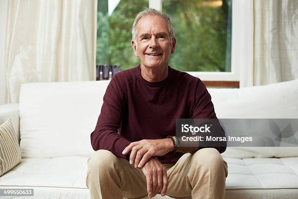 Thoughtful Senior Man Looking Away On Sofa Stock Photo - Download Image Now - Sitting, Senior Adult, Sofa