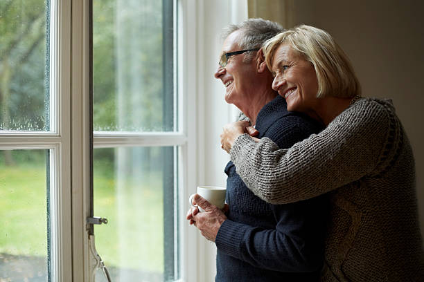 senior woman embracing man in front of door - retirement living fotografías e imágenes de stock