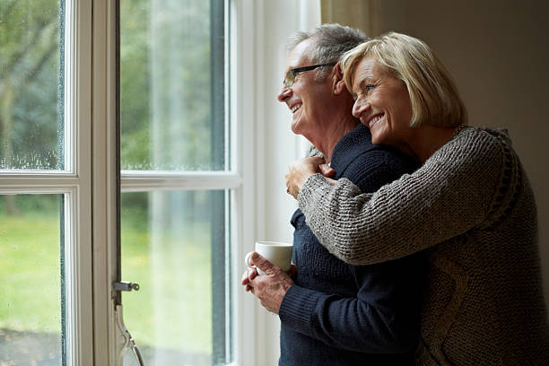 senior woman embracing man in front of door - sexagénaire photos et images de collection