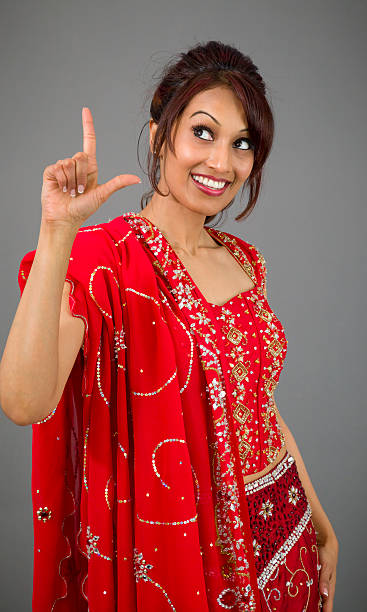 istock Young Indian woman pointing upward and smiling 499551293