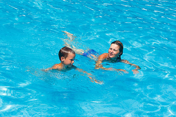 istock Mother train her son to swim in the pool. 499552371