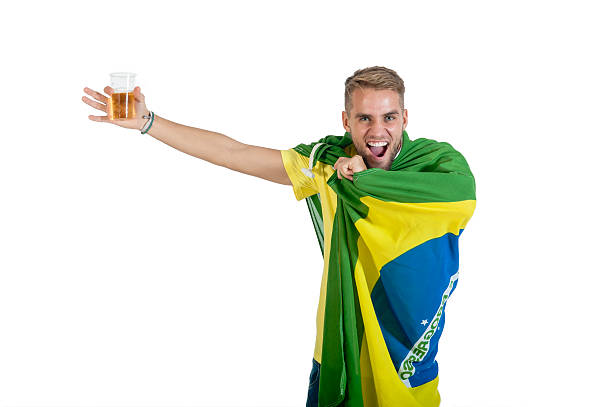 young handsome guy wrapped in brazil flag with beer stock photo