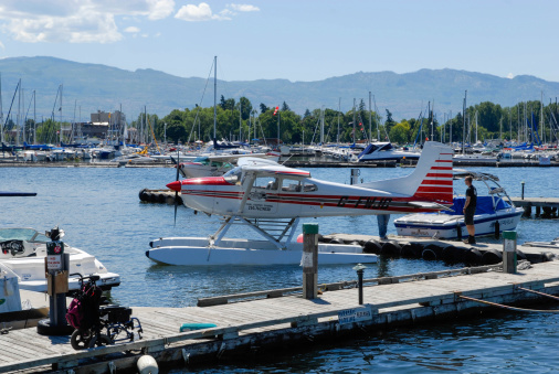 Kelowna,Canada,June,22,2014.A private aircraft operation called Air-Hart Aviation fly,s air charters and tours,and training in and around Kelowna, British Columbia Canada,There is one person standing at rear of the plane on the dock.there is also a number of boats in and around the harbor.