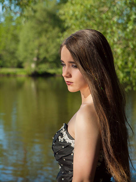 Portrait of beautiful young sad brunette woman wearing colorful dress, standing in a forest.
