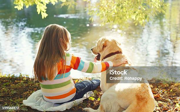 Two Friends Child With Labrador Retriever Dog Sitting In Sunny Stock Photo - Download Image Now