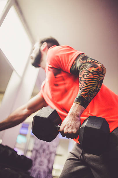 istock Tattooed guy in a gym taking dumbbell from a rack 499568050