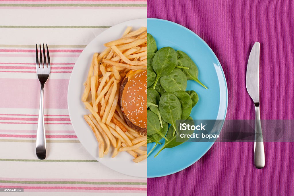 weight loss concept stock image of low fat healthy spinach leaves against unhealthy greasy burger with french fries. diet concept Healthy Eating Stock Photo