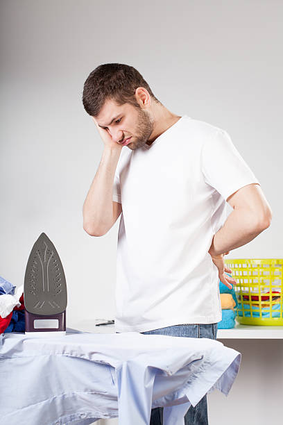 Clumsy man left with ironing A clumsy man not knowing how to iron clothes laundry husband housework men stock pictures, royalty-free photos & images