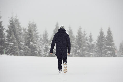 Young man is walking in winter landscape