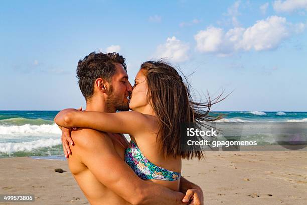 Young Couple Kissing At The Beach In Late Afternoon Stock Photo - Download Image Now