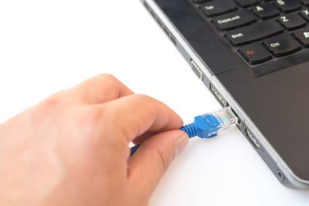 istock hand putting a blue RJ45 network connecting cable to laptop 499577256