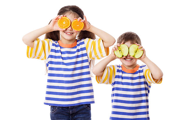 dois engraçado crianças com frutas no rosto - isolated on white fun orange food - fotografias e filmes do acervo