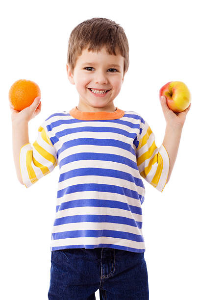 feliz menino segurando uma laranja e de maçã - isolated on white fun orange food - fotografias e filmes do acervo