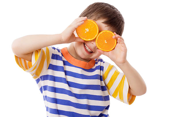 drôle petit garçon avec des fruits frais sur les yeux - isolated on white fun orange food photos et images de collection