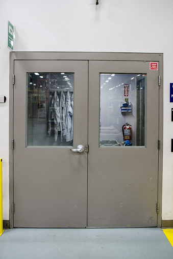 Entrance door of chemical laboratory with smocks on the other side of the doors
