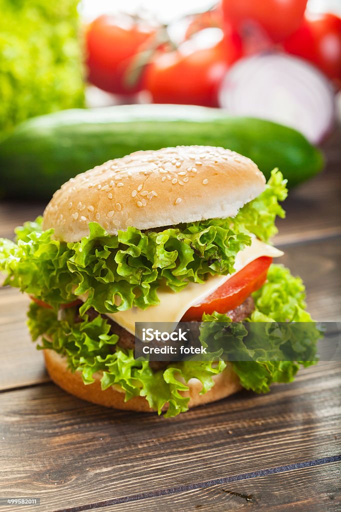 Cheeseburger con lechuga y tomate, cebolla en un nivel de bun de sésamo - Foto de stock de Alimento libre de derechos