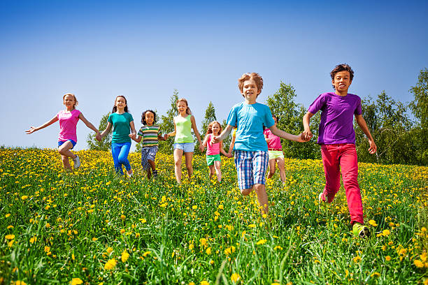 istock Running children holding hands in green meadow 499584739