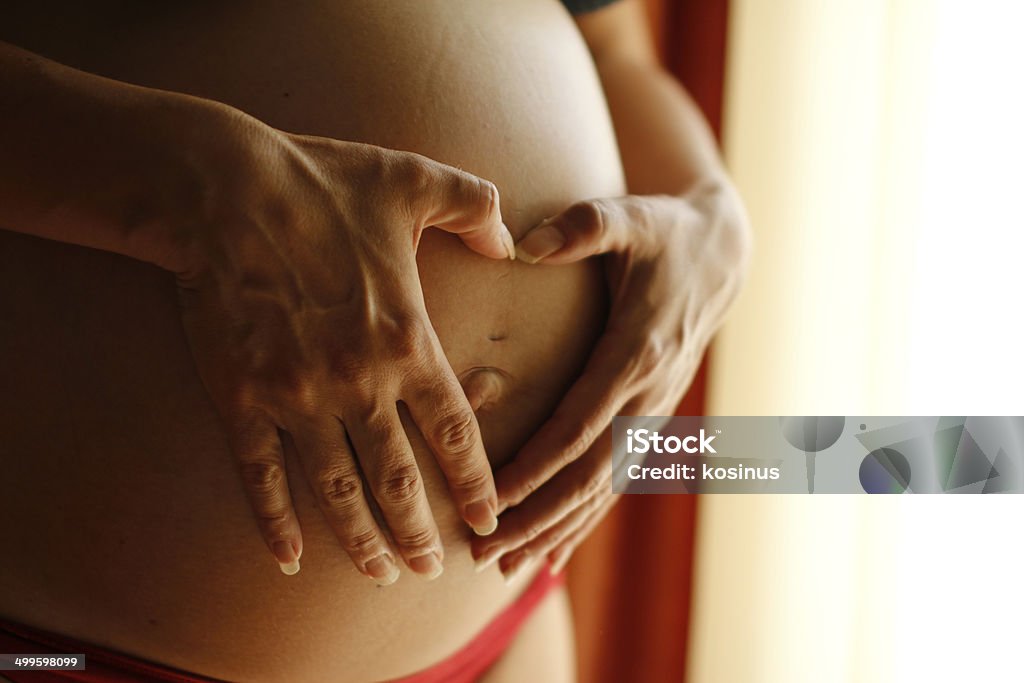 Pregnant woman belly Pregnant woman forming a heart shape with her hands on her belly. Abdomen Stock Photo