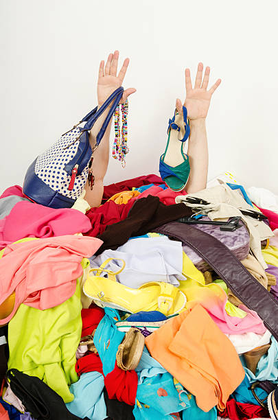 Man hands reaching out from a big pile of clothes. stock photo