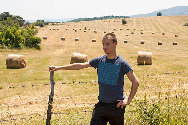 Young farmer show his field with bales