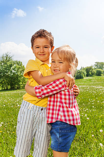 istock Boy and girl hugging in green field 499603081