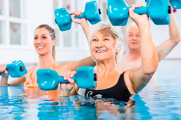 People at water gymnastics in physiotherapy People young and senior in water gymnastics physiotherapy with dumbbells hydrotherapy stock pictures, royalty-free photos & images