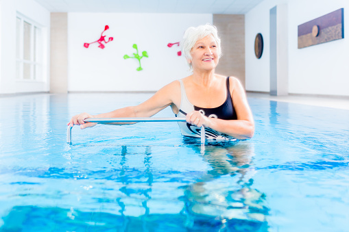 Senior woman in underwater gymnastics therapy with sliding machine