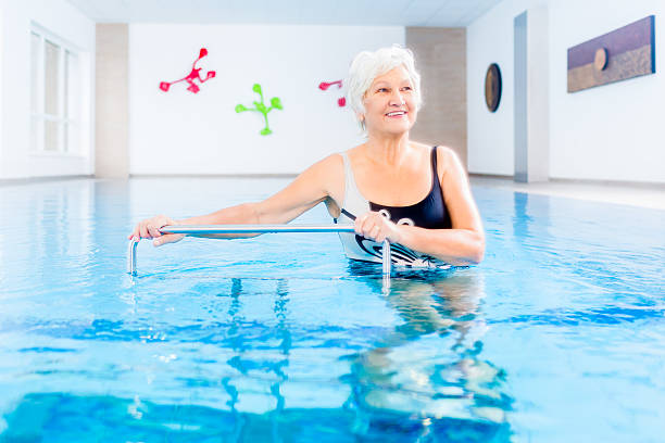 Senior in water gymnastics therapy Senior woman in underwater gymnastics therapy with sliding machine hydrotherapy stock pictures, royalty-free photos & images