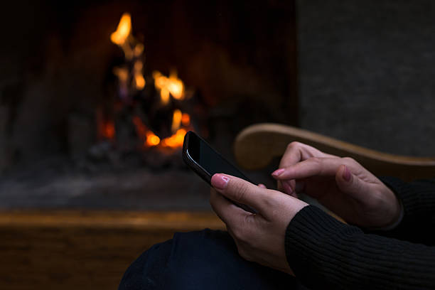 istock Hands holding smartphone against fireplace background 499609844