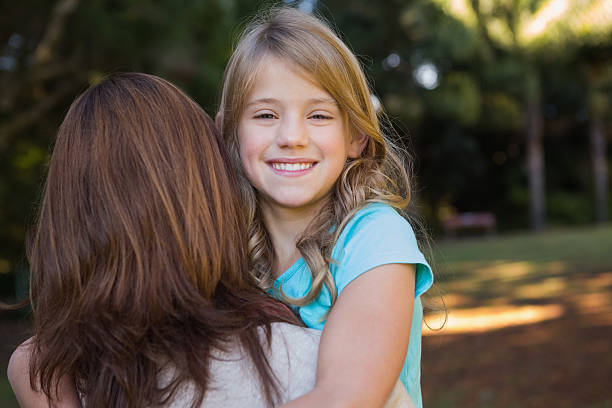 istock Little girl smiling at camera held by her mother 499617113