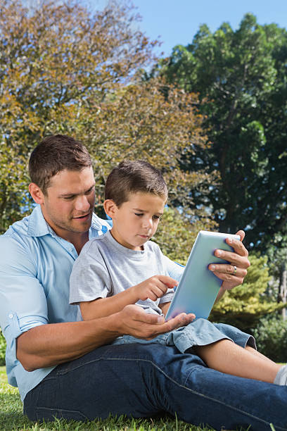 istock Dad and son playing with a tablet pc in park 499618911