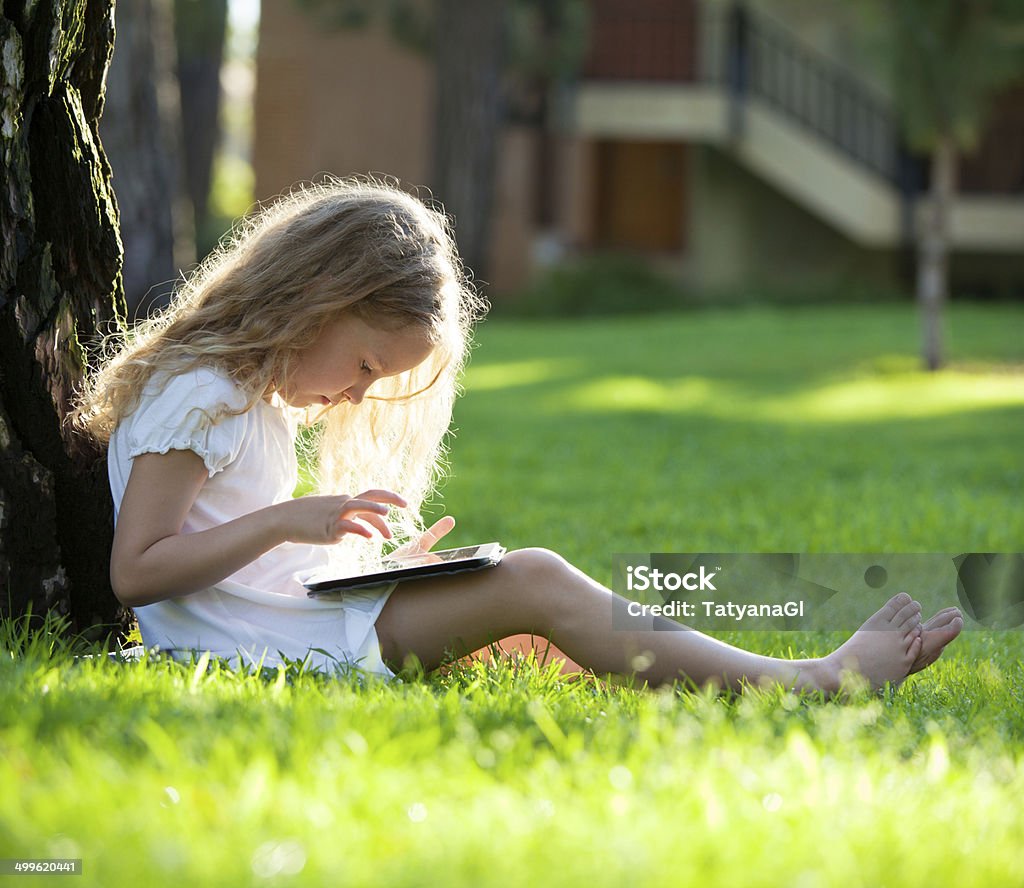 Child with tablet pc outdoors Child with tablet pc outdoors. Little girl on grass with computer Child Stock Photo