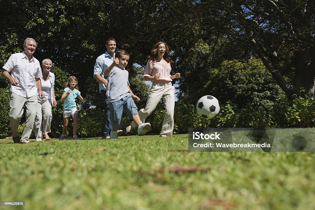 Cheerful multi generation family playing football Cheerful multi generation family playing football in the park Granddaughter Stock Photo