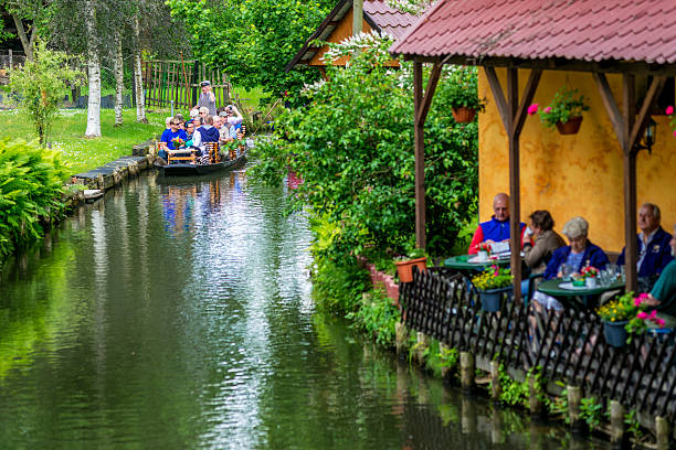 Spreewald cruise in Lehde Lehde, Germany - June 3, 2014: Tourists enjoying the ride on arks (river boats) through the beautiful channels of Lehde, while others having a coffee on a terrace. The Spreewald forest and wetlands (engl. Spree woods) consists of over 200 small canals and waterways of the river Spree which are cutting their way through meadows, forests and along traditional farmhouses. The Spreewald´s main area around Lübbenau and Lehde is located about 100 km south-east of Berlin. In 1991 it was designated as biosphere reserve by UNESCO. spreewald stock pictures, royalty-free photos & images