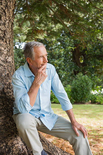 istock Thoughtful mature man sitting on tree trunk 499621783