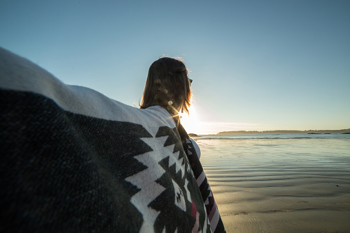 Young woman on the beach in autumn arms outstretched for positive emotions.