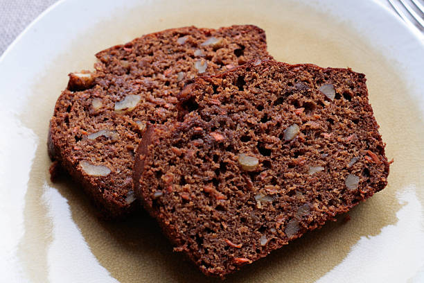 Carrot Walnut Bread Two slices of freshly baked carrot walnut bread on a light yellow plate. carrot cake day stock pictures, royalty-free photos & images