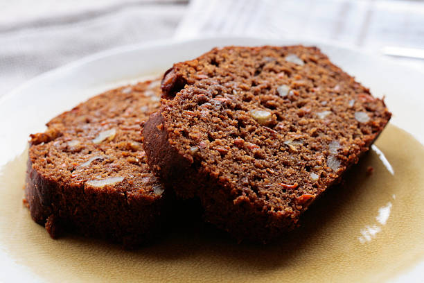 Carrot Walnut Bread Two slices of freshly baked carrot walnut bread on a light yellow plate. carrot cake day stock pictures, royalty-free photos & images
