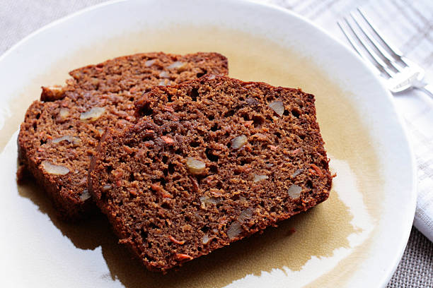 Carrot Walnut Bread Two slices of freshly baked carrot walnut bread on a light yellow plate. carrot cake day stock pictures, royalty-free photos & images