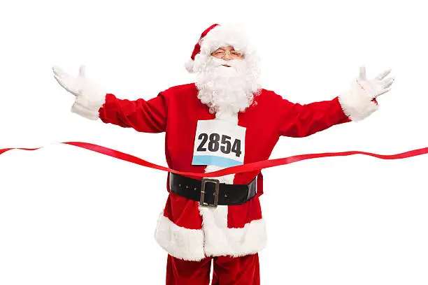 Studio shot of Santa Claus wearing a race number on his chest and crossing the finish line isolated on white background