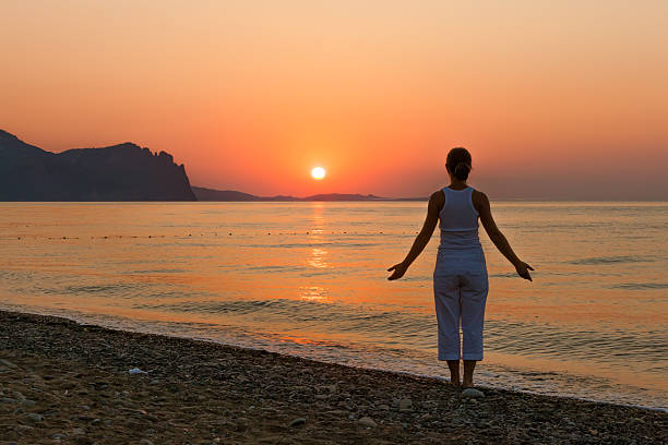Kobieta robi rano excercises w morzu podczas wschód słońca – zdjęcie