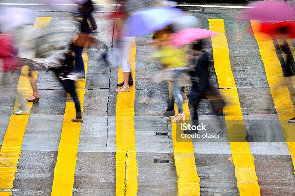 Motion blurred pedestrians crossing Hong Kong street in the rain Crowd in central Hong Kong. Adult Stock Photo