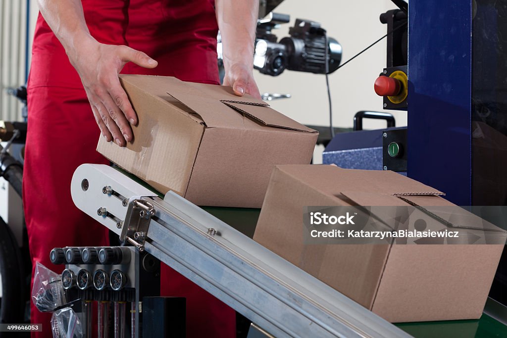Worker putting a box on conveyor belt Close-up of worker putting a box on conveyor belt for shipping Activity Stock Photo