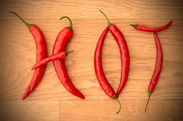 istock Red Cayenne Chilli Pepper Letters Spelling HOT on Wooden Table 499647606