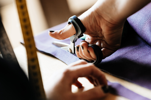 Close-up shot of hands of a woman cutting fabrics