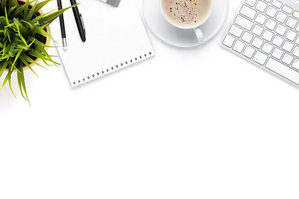 Photo of Office desk table with computer, supplies, coffee cup and flower